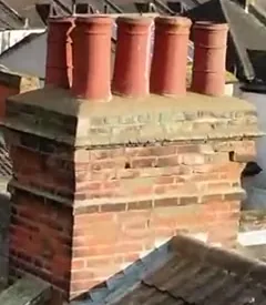 Terracotta chimney pots surrounded by shaped top mortar above a brick chimney