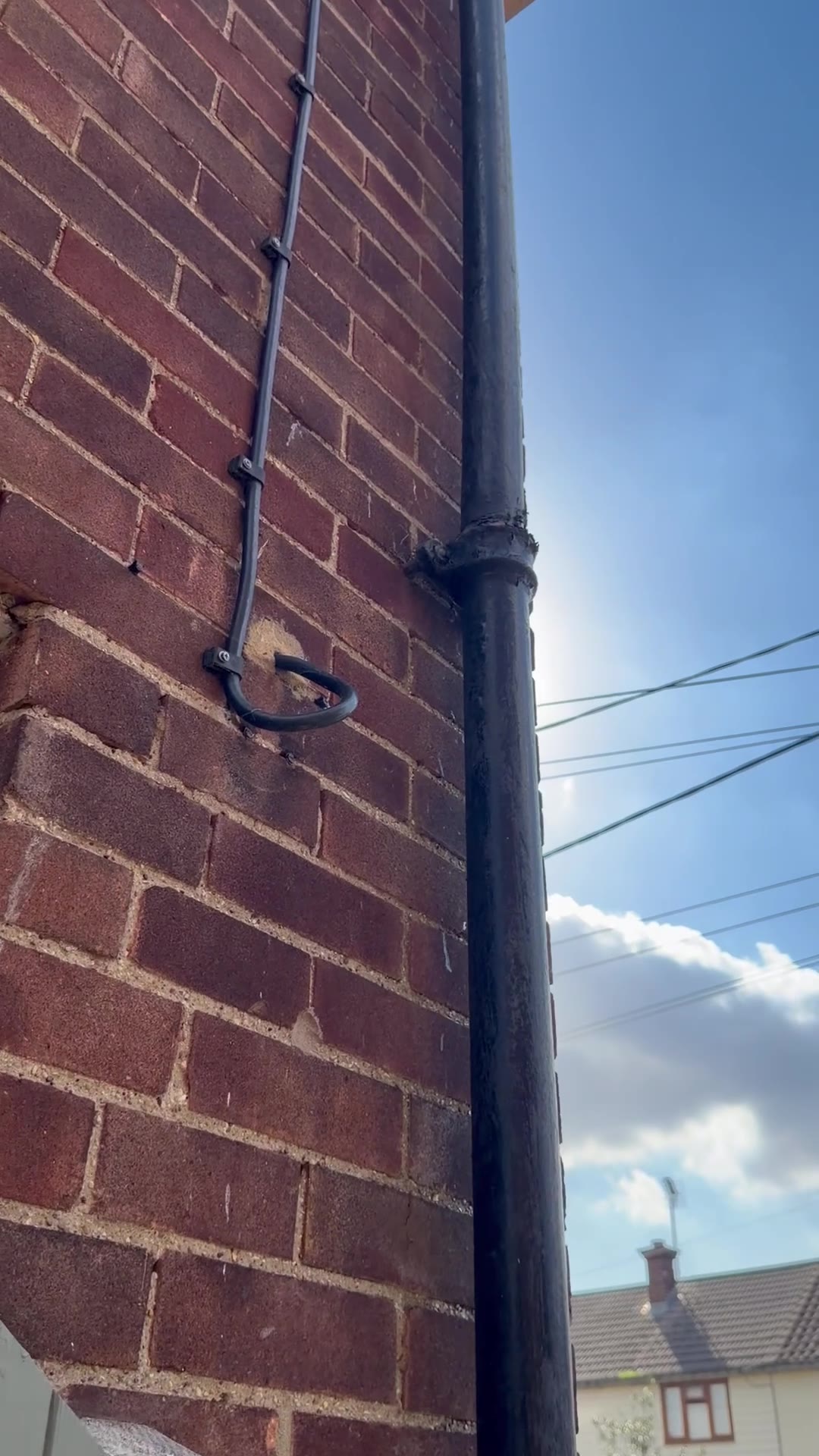 Old cast-iron downpipe joint and fixing against a brick wall