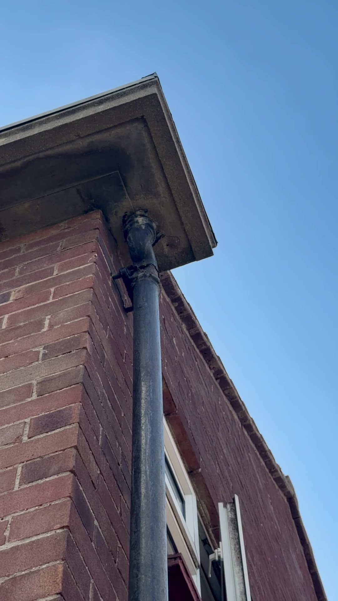 Deteriorated cast-iron downpipe and upper joint below the eaves