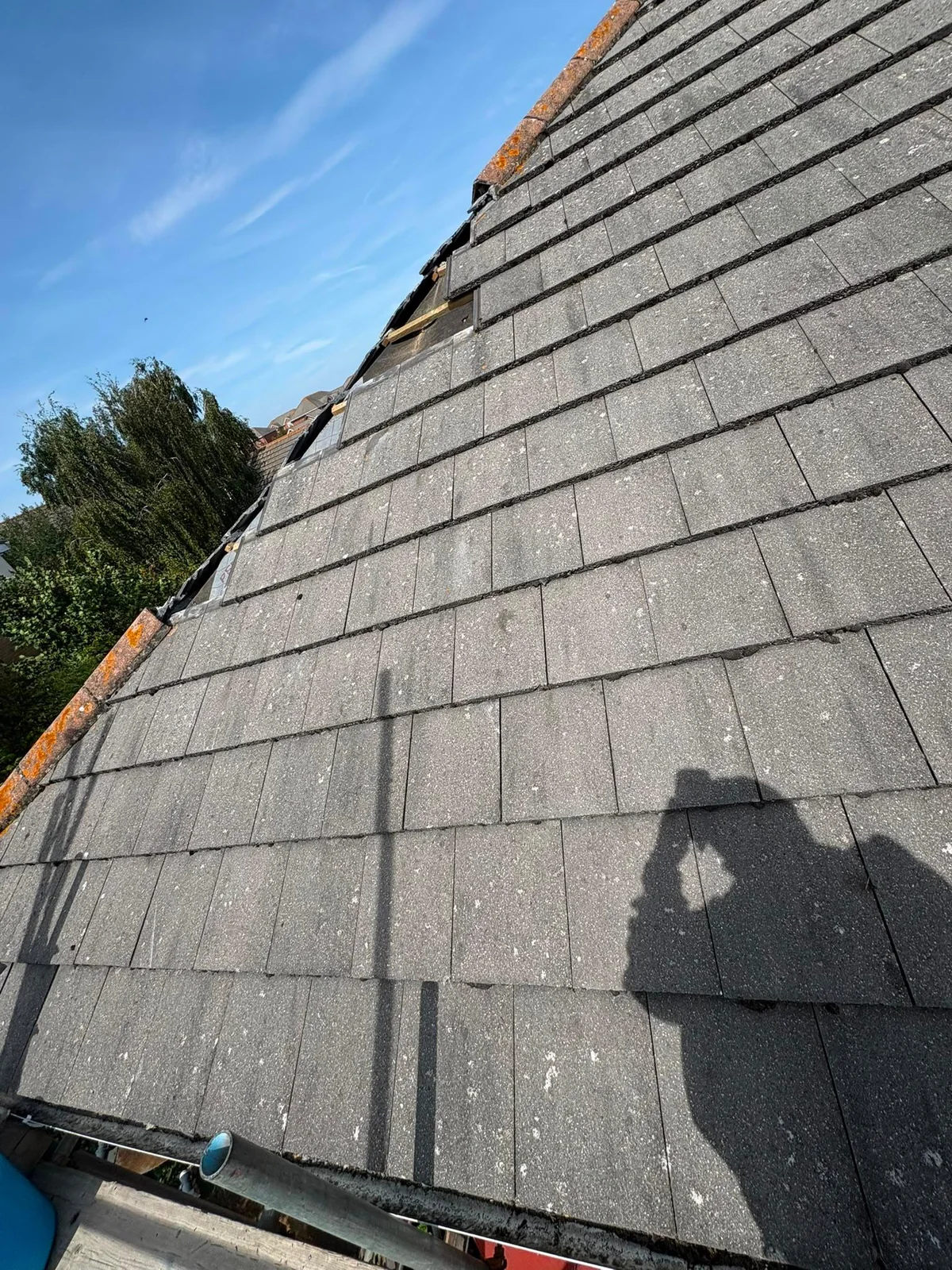 Roof tiles removed along a hip, exposing battens and underlay