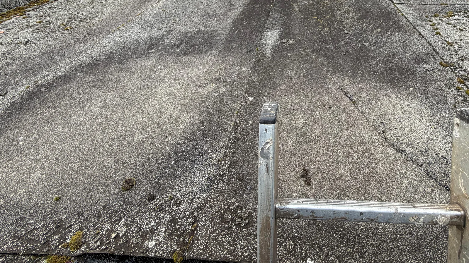 Weathered flat-roof covering with seams and moss near the perimeter